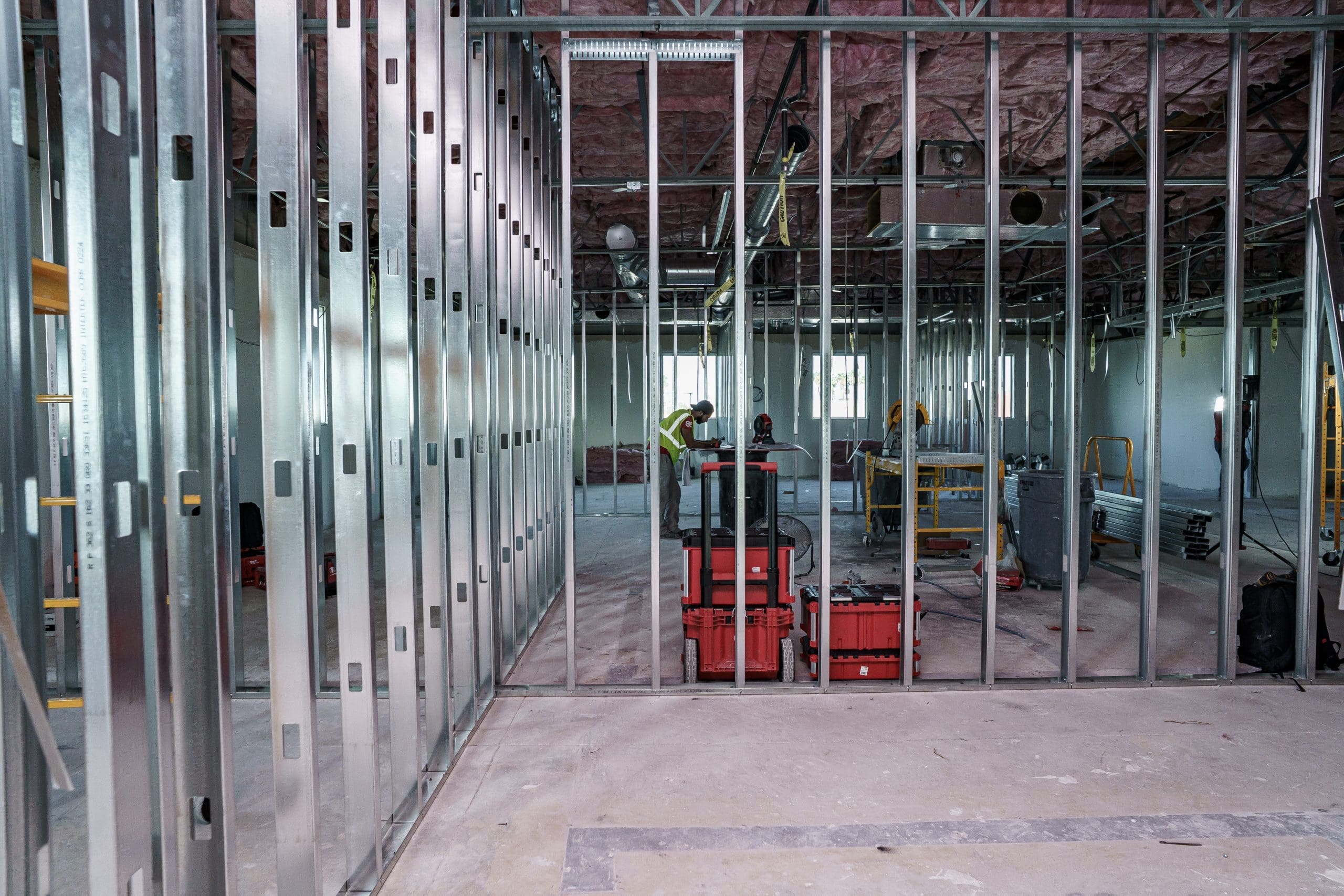 Metal framing in a commercial office construction site. Can see red tools boxes through the framing.