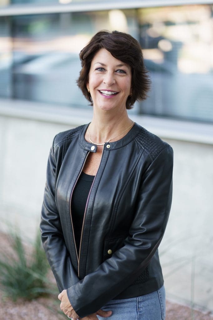 Headshot of Stephanie Trenter wearing a black leather jacket and she has brown short hair.