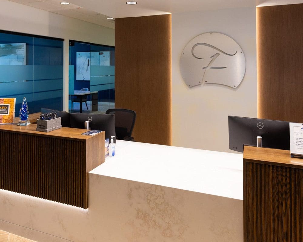 Modern office reception area with a marble counter, wood paneling, two computer monitors, and a large logo on the wall—expertly crafted through top-tier general contracting services Arizona businesses trust.